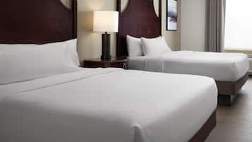A hotel room with two large beds, a nightstand with a lamp, and a window with curtains.