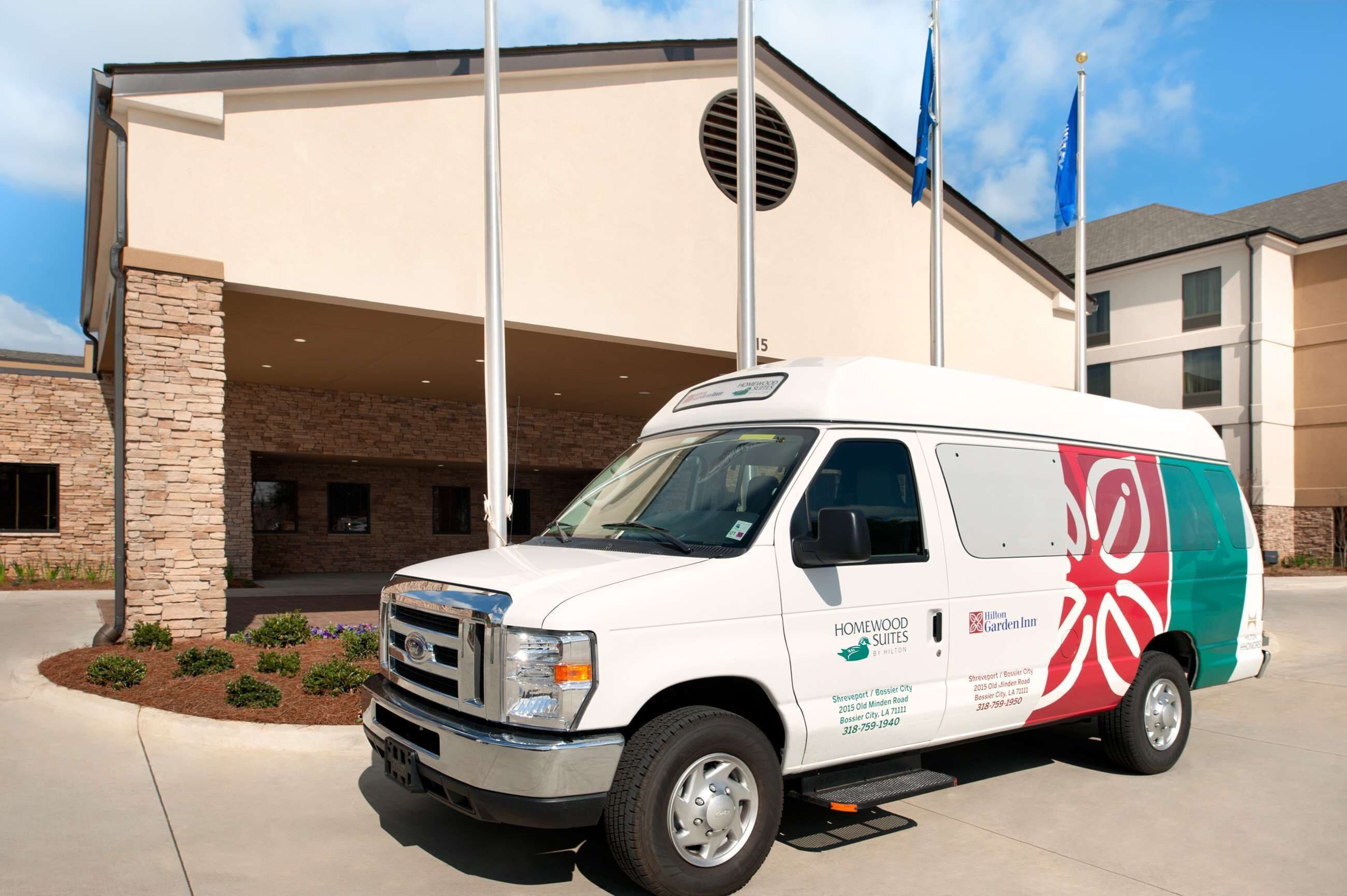 A white van parked in front of a building with a stone facade and a large entrance.