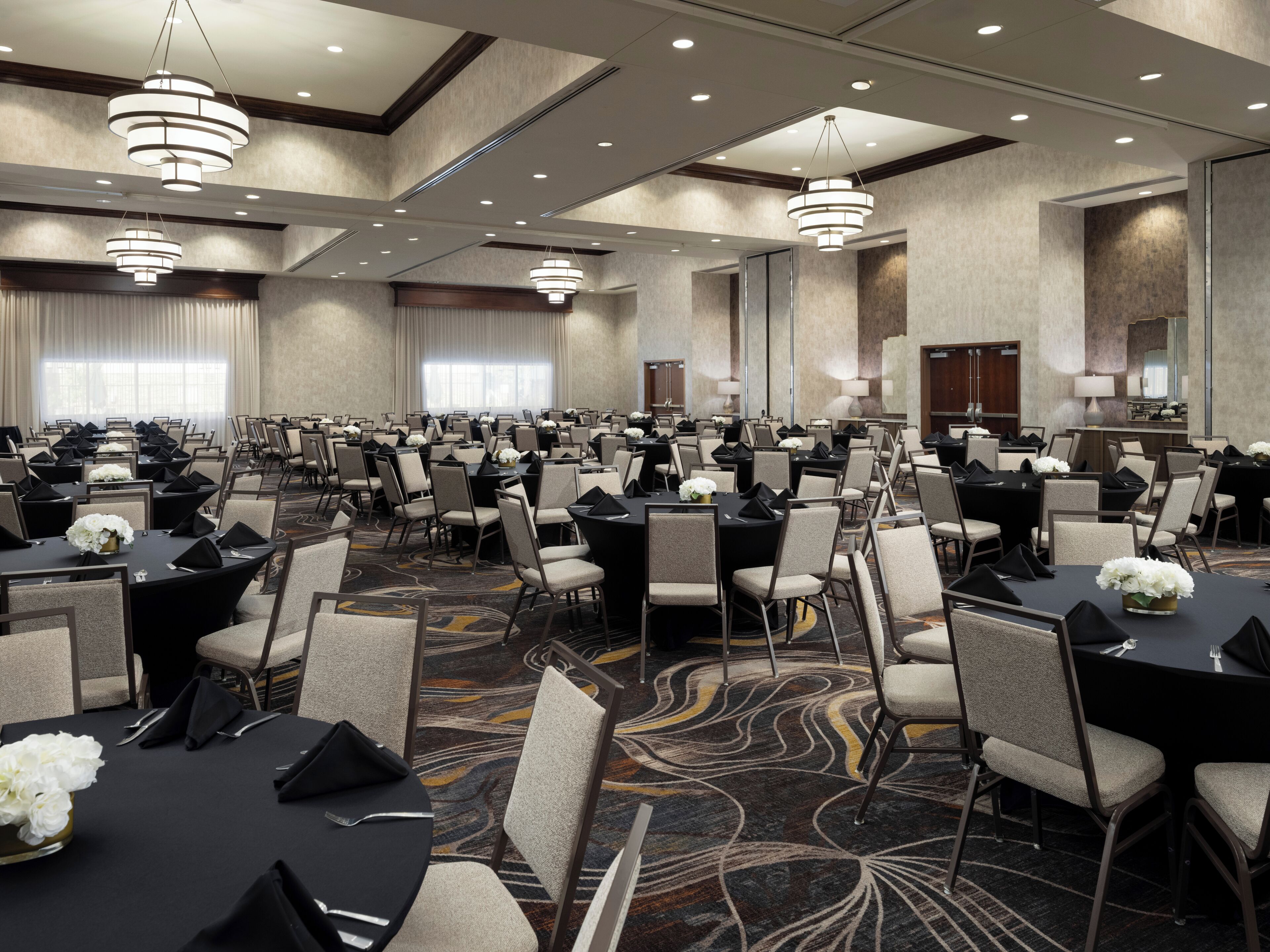 A large conference room with multiple tables and chairs, arranged in rows.