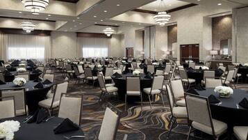 A large conference room with multiple tables and chairs, arranged in rows.