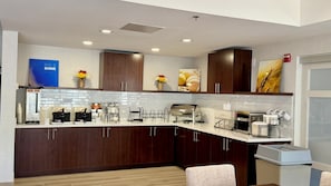 A modern kitchen with dark wood cabinets, white countertops, and various appliances including a coffee machine and toaster. - Comfort Inn & Suites Sturbridge - Brimfield (Sturbridge)