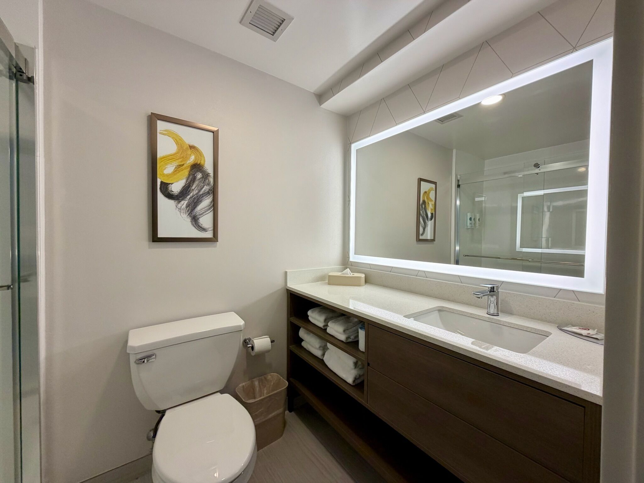 A modern bathroom with a toilet, sink, and mirror.