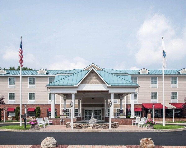 A hotel with a covered entrance, flagpoles, and outdoor seating.