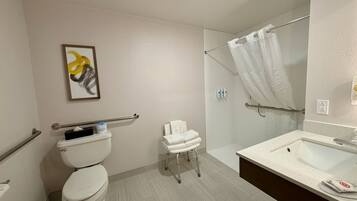 A bathroom with a toilet, a shower with a glass door, a sink, and a towel rack.