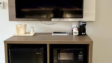 A kitchenette with a microwave, a coffee maker, a refrigerator, and a flat-screen TV mounted above the counter.