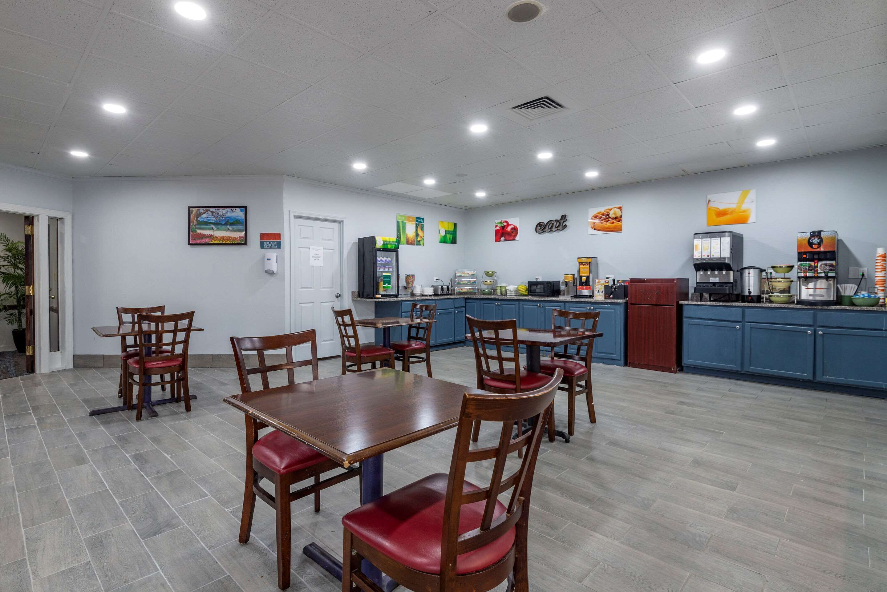 A dining area with wooden tables and chairs, a kitchen area with blue cabinets, and various food and beverage dispensers.