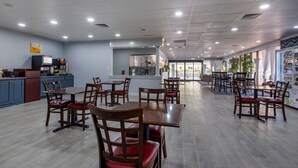 A spacious restaurant with multiple dining tables and chairs, a kitchen area, and large windows allowing natural light. - Quality Inn Rock Hill Northeast I-77 (Rock Hill)