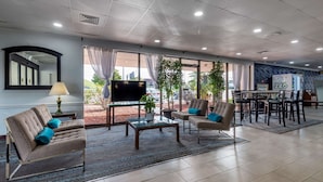A hotel lobby with a sofa, armchairs, a coffee table, a TV, and a vending machine. - Quality Inn Rock Hill Northeast I-77 (Rock Hill)