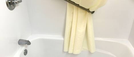 A white bathtub with a shower curtain rod and a towel.