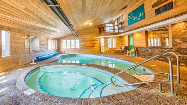 An indoor swimming pool with a wooden interior, a balcony with a view, and a sign for Quality Inn. - Quality Inn Saint Ignace I-75 (St Ignace)