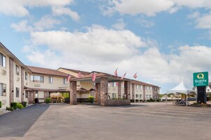 Un hotel con estacionamiento, una entrada techada y banderas estadounidenses.