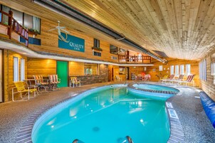 Una piscina techada con múltiples carriles, sillas de descanso y un letrero que dice Quality Inn.