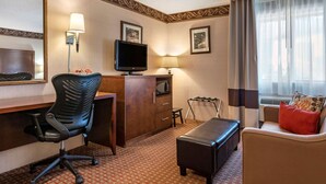 A hotel room with a desk, chair, television, and a sofa. - Quality Inn Saint Ignace I-75 (St Ignace)