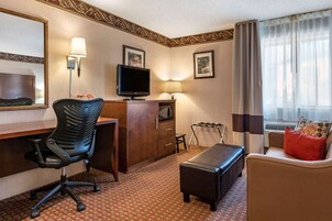 Una habitación de hotel con escritorio, silla, televisión y sofá.