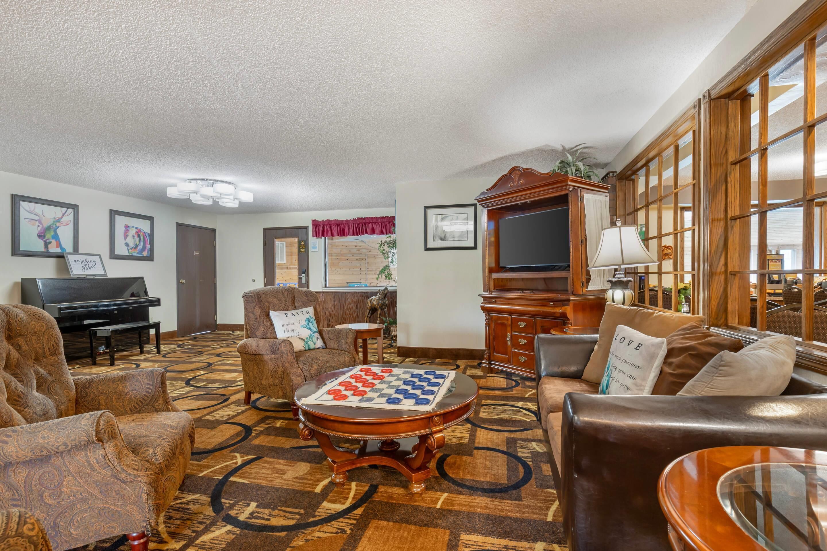 Un salón espacioso con un piano de cola, un mueble de madera grande y un televisor.