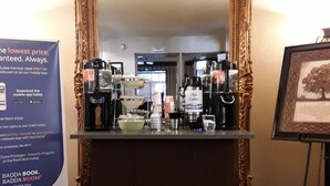 A hotel reception area with a large ornate mirror, a coffee station, and a framed picture on the wall. - Quality Inn Saint Ignace I-75 (St Ignace)