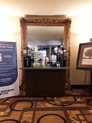 A hotel reception area with a large ornate mirror, a coffee station, and a framed picture on the wall. - Quality Inn Saint Ignace I-75 (St Ignace)