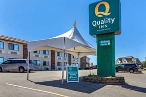 Señal de Quality Inn, una tienda de campaña y un letrero que indica zona de estacionamiento de motocicletas.