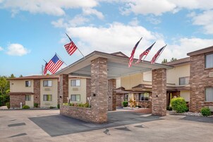 Un hotel con un área exterior techada, varias banderas estadounidenses y fachada de ladrillo.