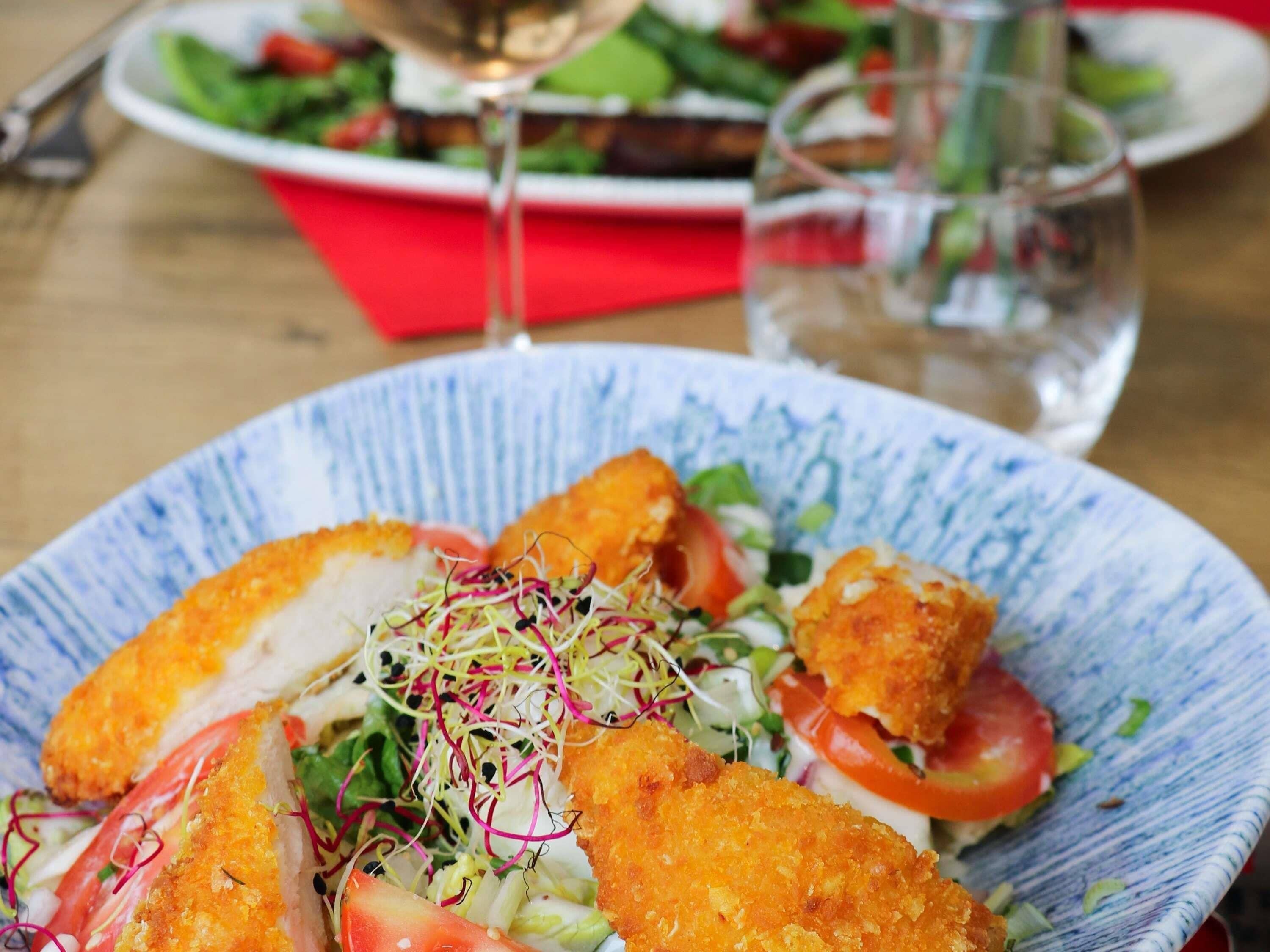 Une assiette de nourriture, avec une salade et un verre de vin, sur une table.