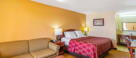 Une chambre d’hôtel avec un lit, un canapé, un bureau et une chaise.