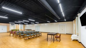 A spacious indoor area with a high ceiling, wooden flooring, and rows of chairs. - Econo Lodge Gaffney (Gaffney)