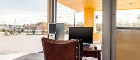 A room with a large window, a desk with a computer, and a chair.
