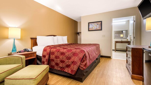 A hotel room with a bed, a desk, a chair, a TV, and a bathroom visible through an open door. - Econo Lodge Gaffney (Gaffney)