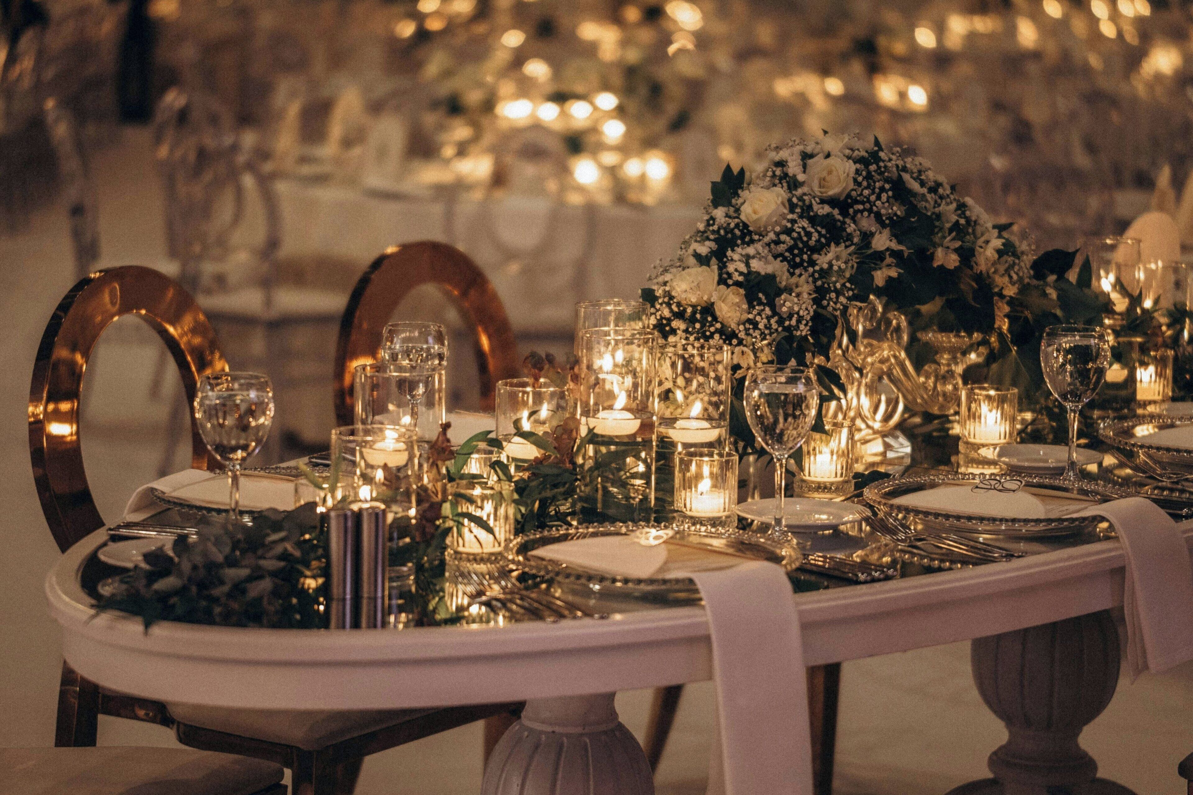 A table set for a formal event with candles, glassware, and floral centerpieces.