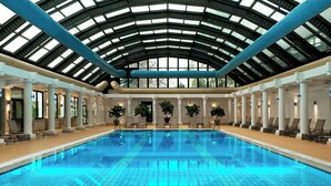 A large indoor swimming pool with a high, arched glass ceiling, surrounded by columns and lounge chairs. - Sheraton Ankara Hotel & Convention Center (Ankara)
