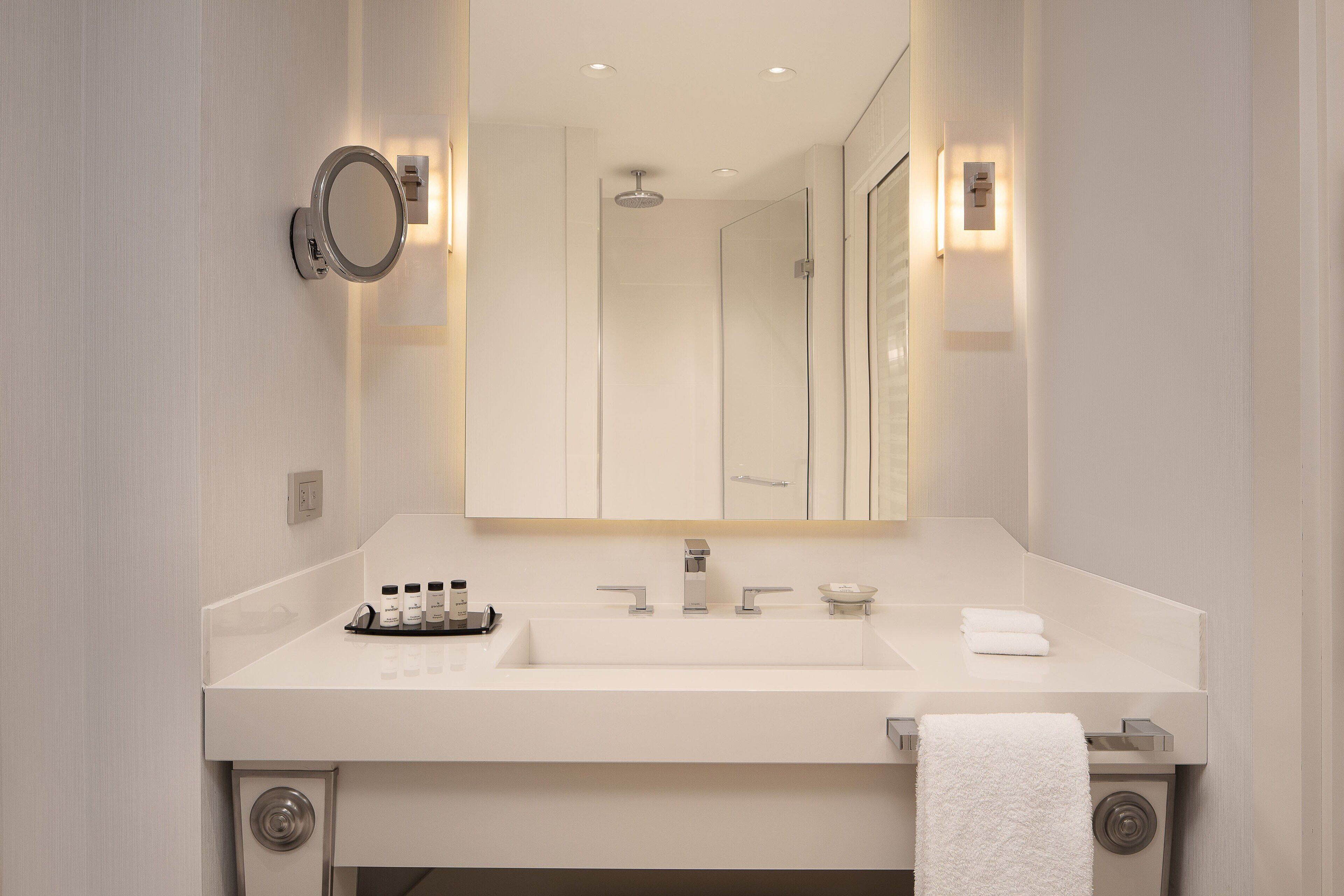 A modern bathroom with a large mirror, two sinks, and a towel rack.