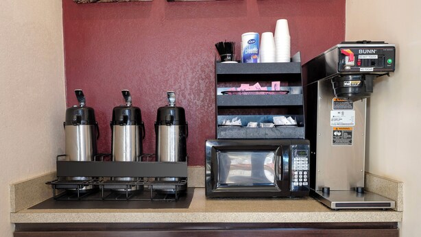 A kitchenette with a coffee machine, a microwave, and a Bunn coffee maker. - Red Roof Inn Atlanta - Suwanee/ Mall of Georgia (Suwanee)
