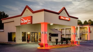 A Red Roof Inn with a lobby entrance, a visible staircase, and a parking lot. - Red Roof Inn Atlanta - Suwanee/ Mall of Georgia (Suwanee)