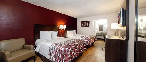 A hotel room with a large bed, a sofa, a desk, and a mirror.