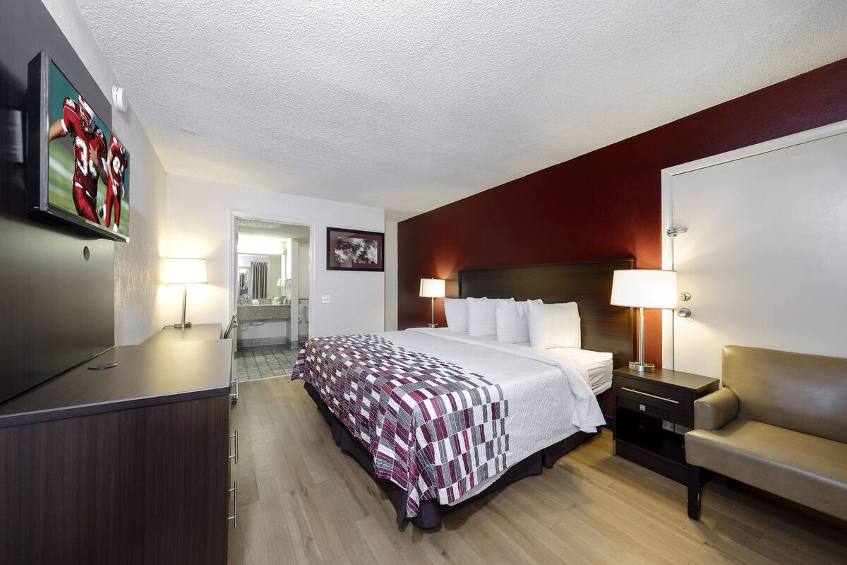 A hotel room with a bed, bedside tables, a TV, and a desk.