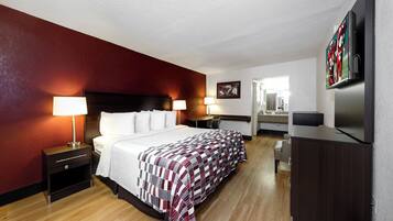 Una habitación de hotel con cama, lámparas de noche, escritorio, televisión y espejo.