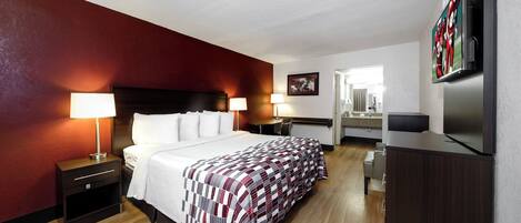 A hotel room with a bed, bedside lamps, a desk, a television, and a mirror.