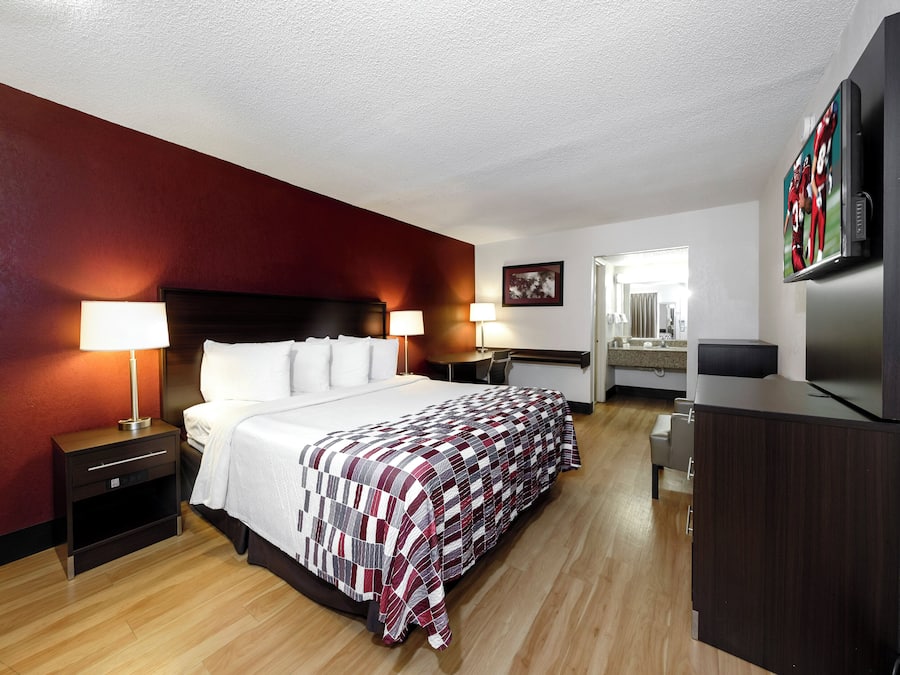 Una habitación de hotel con cama, lámparas de noche, escritorio, televisión y espejo.