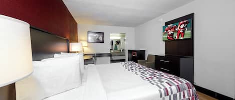 A hotel room with a bed, a desk, a television, and a mirror.