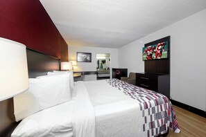 A hotel room with a bed, a desk, a television, and a mirror.