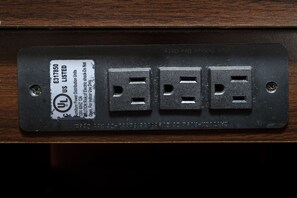 A black electrical outlet plate with three sockets and a label indicating it is UL listed. - Red Roof Inn Atlanta - Suwanee/ Mall of Georgia (Suwanee)