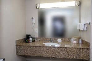 A bathroom with a granite countertop, a sink, a hairdryer, and a towel rack. - Red Roof Inn Atlanta - Suwanee/ Mall of Georgia (Suwanee)