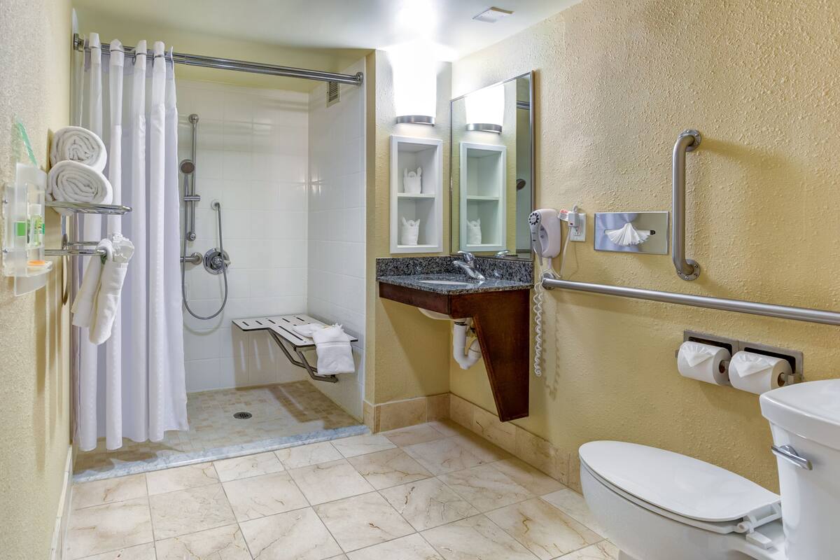 A bathroom with a shower, toilet, sink, and towel rack.