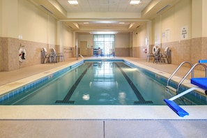 A large indoor swimming pool with clear lanes, safety chairs, and a lifeguard chair.