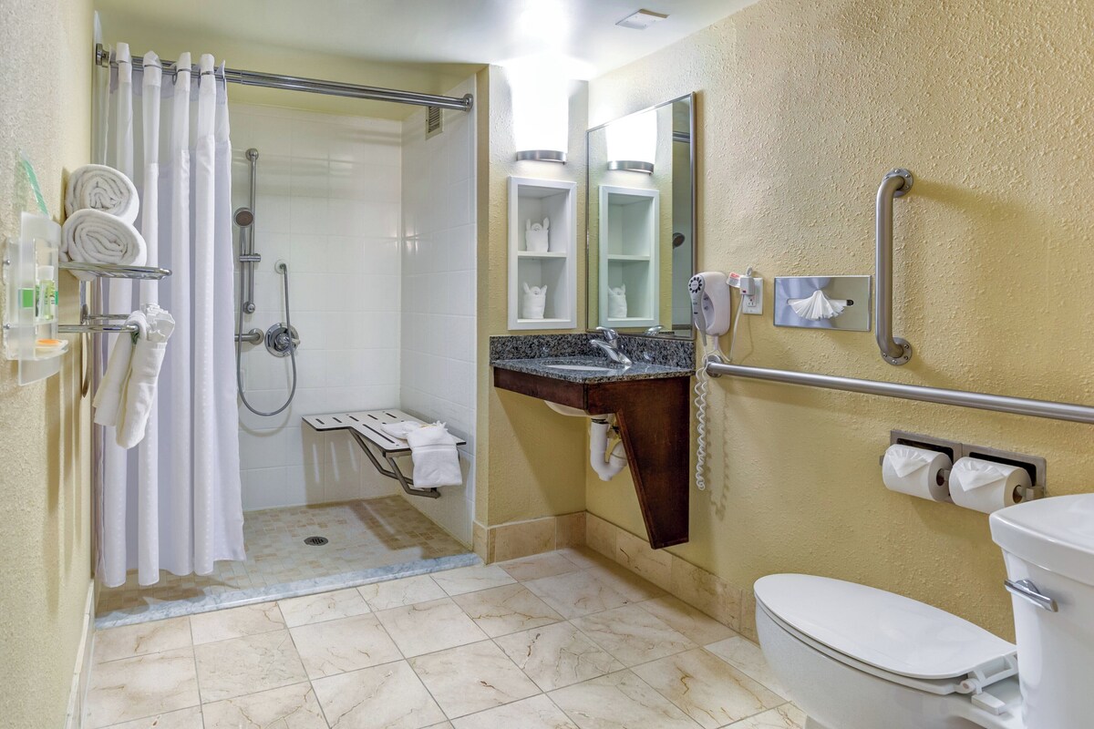 A bathroom with a shower, toilet, sink, and towel rack.