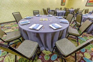 Une salle de conférence avec une table ronde, des chaises et un sol recouvert de moquette.
