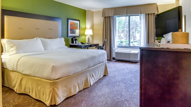 A hotel room with a large bed, a desk, a television, and a window with curtains. - Holiday Inn Indianapolis Carmel by IHG (Indianapolis)