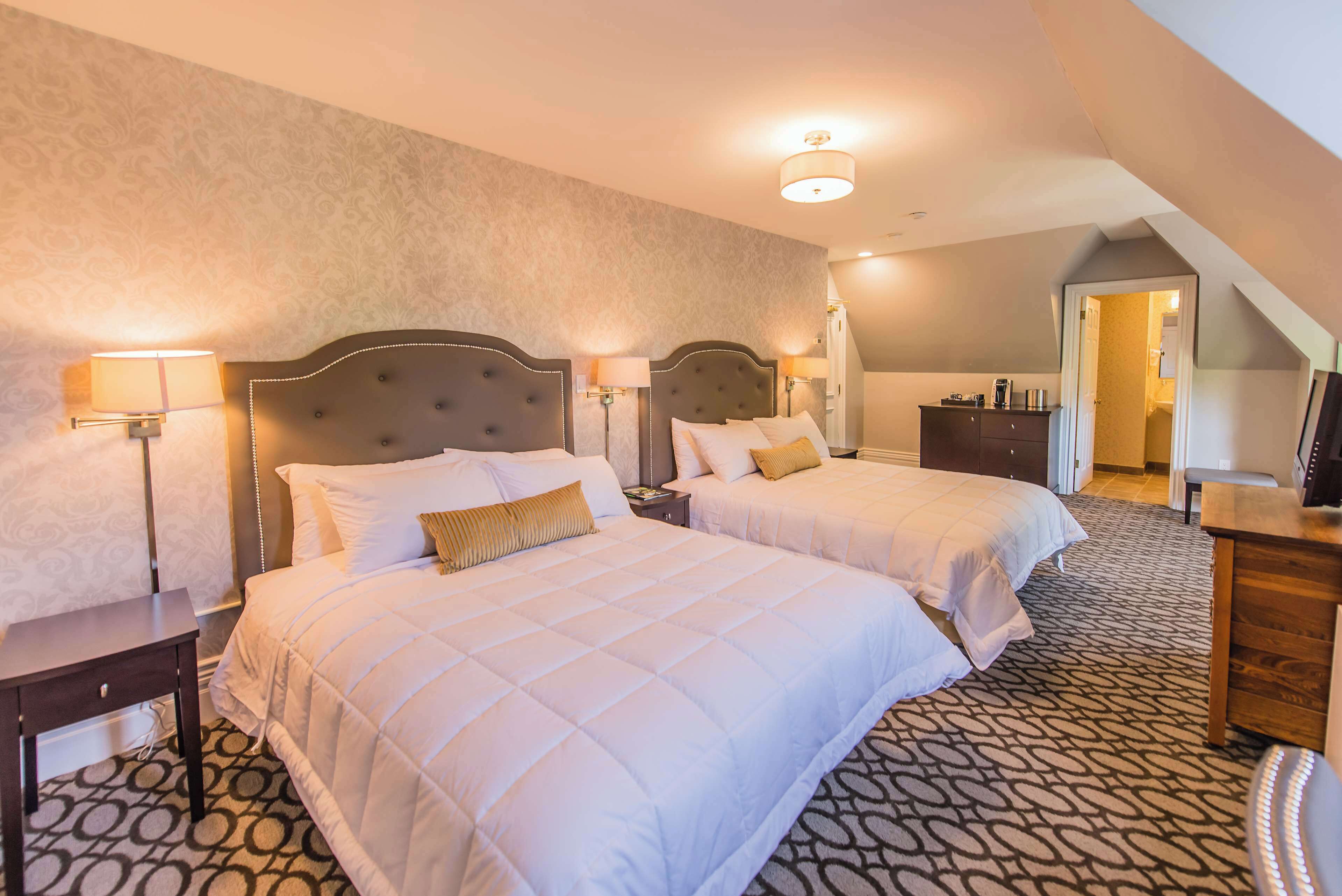 Une chambre d’hôtel avec deux lits, un bureau et une armoire.