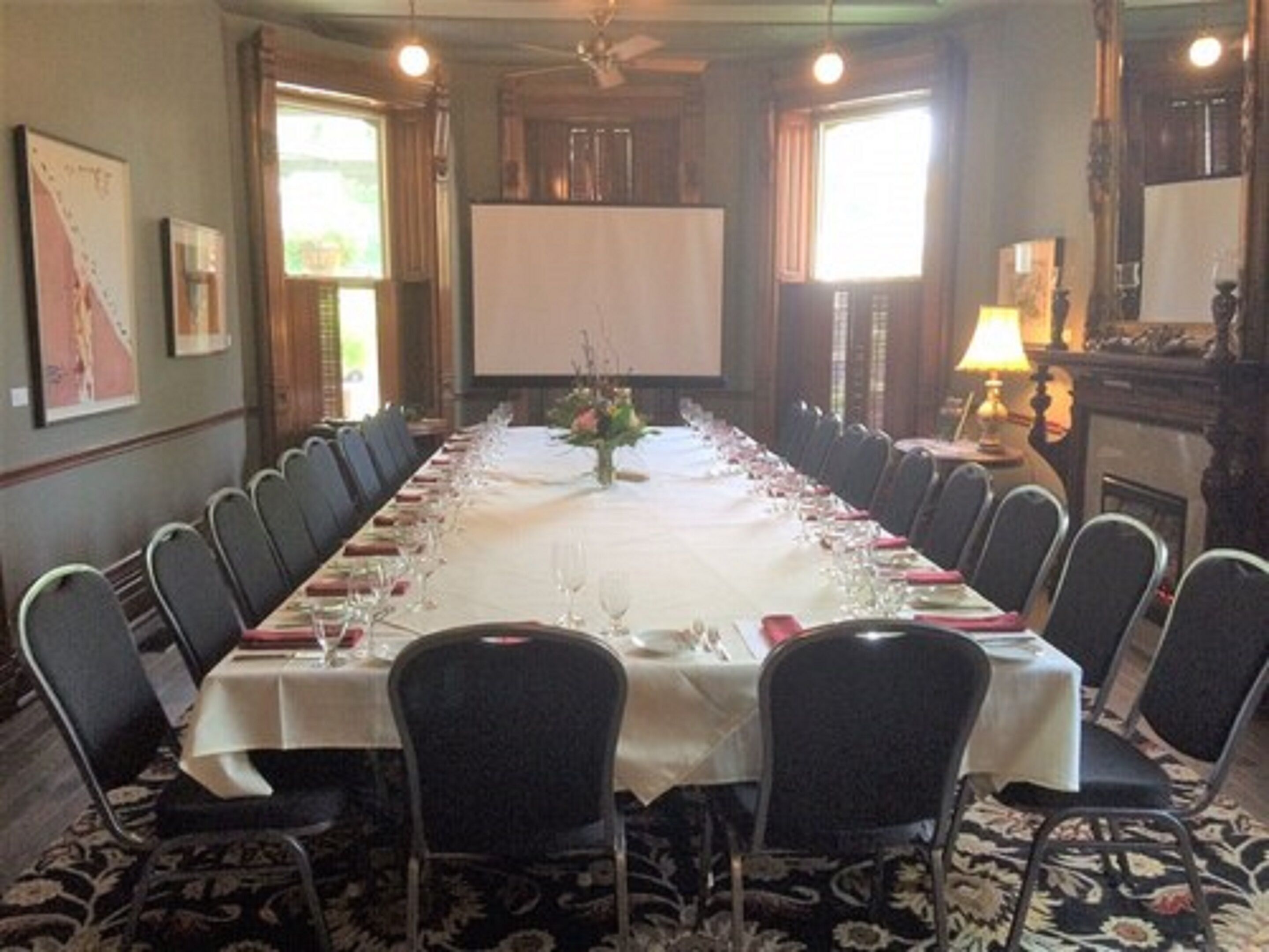 A long conference table with chairs, a projector screen, and a fireplace.