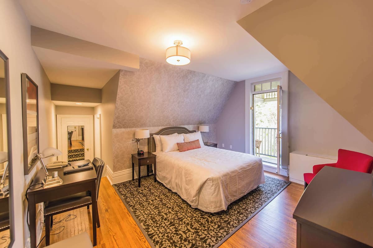 A bedroom with a bed, bedside tables, a desk, and a chair.